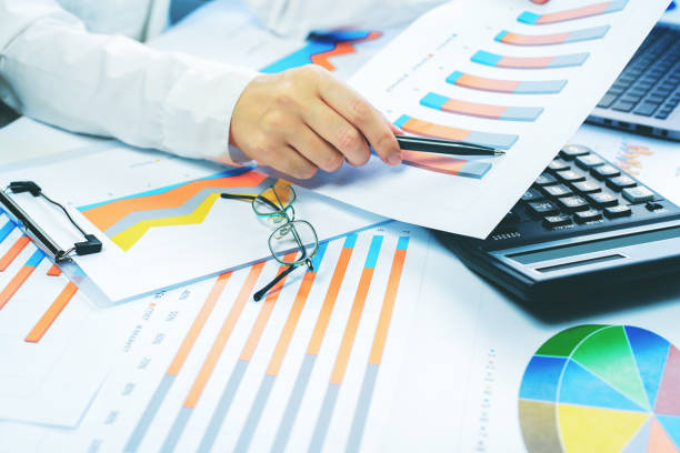 istock Finance. Female hand with calculator on financial graphs on desk 1257158370