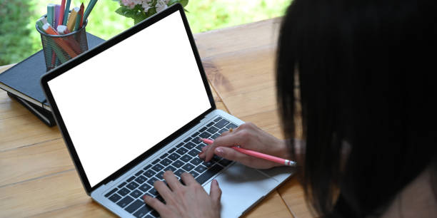 istock Cropped image woman is using a white blank screen computer laptop at the wooden working desk. 1257158410
