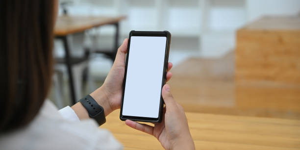 istock Cropped image hands are holding a white blank screen smartphone in the comfortable living room. 1257158493