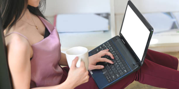 istock Cropped image woman is drinking coffee and using a mockup computer laptop. 1257158544