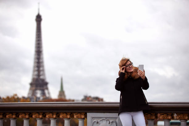 istock Girl using cellphone with Paris city background, Seine river and Eiffel tower. 1257161144