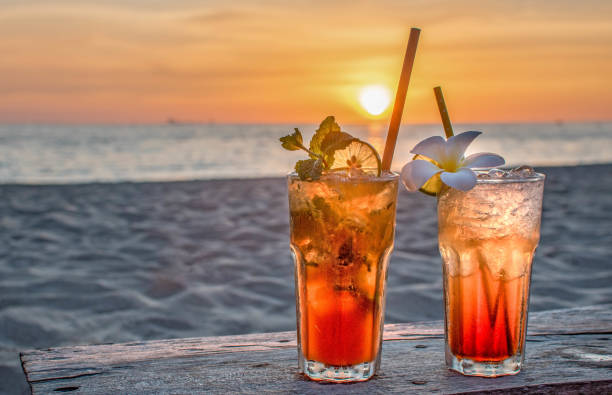 bebidas con playa borrosa y puesta de sol en el fondo - barbados fotografías e imágenes de stock