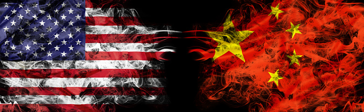 American and Chinese flags in smoke shape on black background. Concept of conflict war and custom duty. America VS China metaphor. Dollar Yuan exchange currency and international commercial tension.