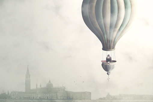 man with mask on a big balloon flying over Venice Italy