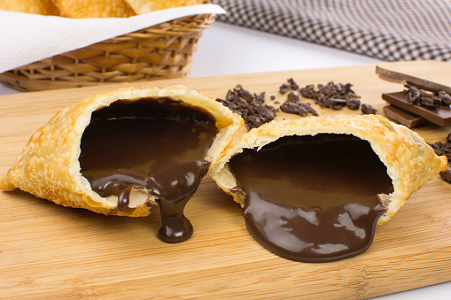 One open tradional Brazilian fried pastry called pastel stuffed with chocolate Brazilian dessert brigadeiro with in a cutting board