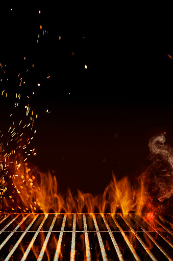 Empty steel barbecue BBQ grill grate with flaming fire, sparks and smoke on black background. Ready for the placement of your food. Cooking concept. Template, mockup. Close up, copy space