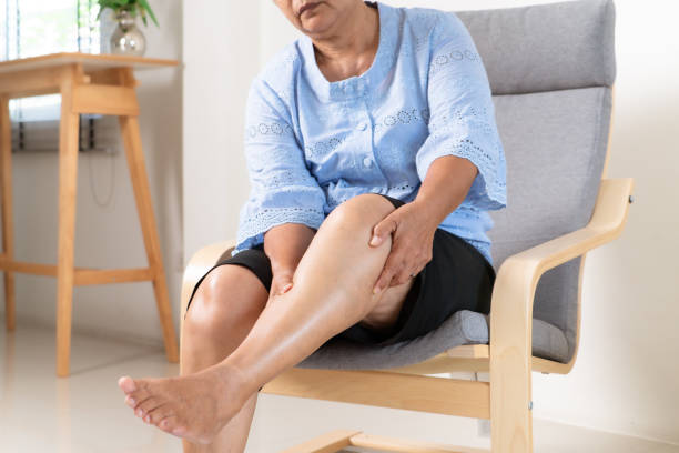 mujer mayor que sufre de dolor de rodilla en casa, concepto de problema de salud - calambres fotos fotografías e imágenes de stock