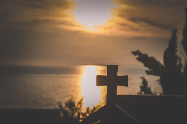 views to the christian cross in the building by the sea at orange sunset time