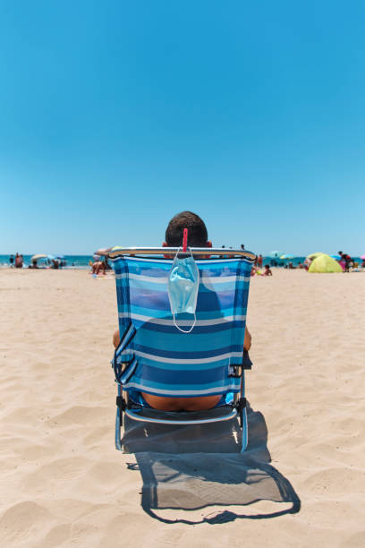 istock mask and man sitting in a deck chair on the beach 1257175154