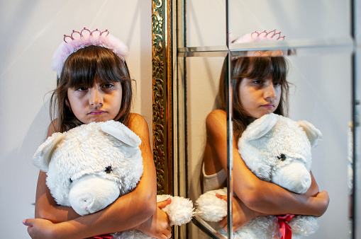 Turkish little girl with her teddy by mirror