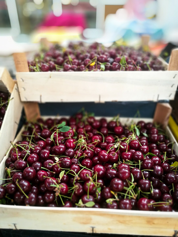 Selective focus color image depicting a pile of fresh organic cherries for sale on a market stall at a fruit and vegetable market.