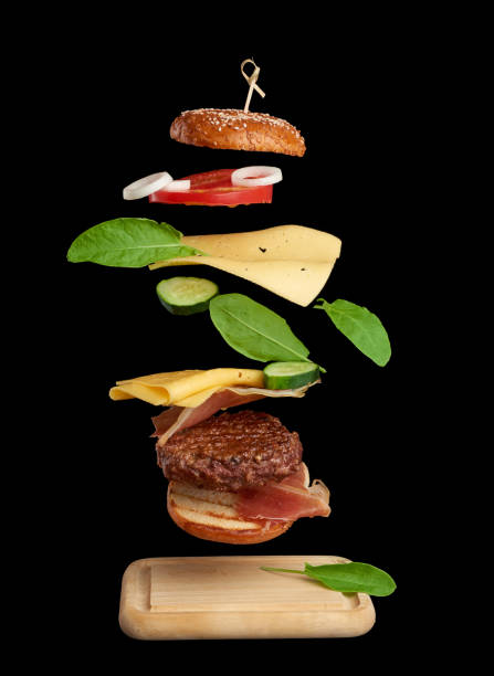 istock levitating cheeseburger ingredients: juicy meat cutlet, cheddar cheese, sesame bun, lettuce, white onion rings, slice of tomato, cucumber 1257177113