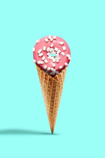 istock Sweet donut glazed by pink icing sprinkled with marshmallow in wafer cone on turquoise background. Treats, unhealthy nutrition. Close up, copy space 1257178541