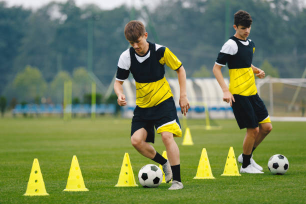 Boys on soccer football training. Young players dribble ball between training cones. Players on football practice session. Soccer summer training camp Boys on soccer football training. Young players dribble ball between training cones. Players on football practice session. Soccer summer training camp sports training drill stock pictures, royalty-free photos & images