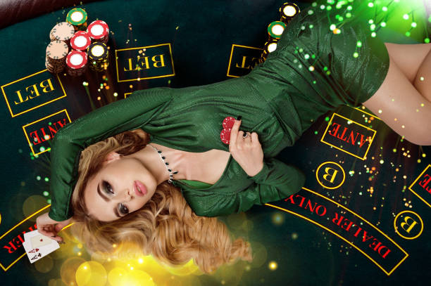 blondynka w zielonej sukience pokazuje czerwone frytki i asy. leżąc na stole z kolorowymi blaskami nad nią. poker, kasyno. zbliżenie, widok z góry - gambling chip green stack gambling zdjęcia i obrazy z banku zdjęć
