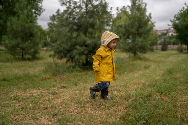 istock Little boy walking outdoors and jumping on puddle 1257180097