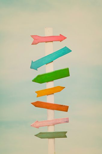 Colorful wooden direction arrow signs on a wooden pole