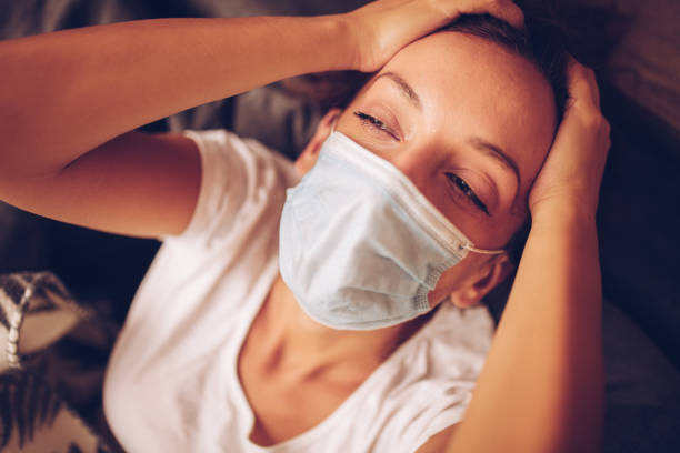 istock Girl lying in bed with cat wearing protective mask 1257190284
