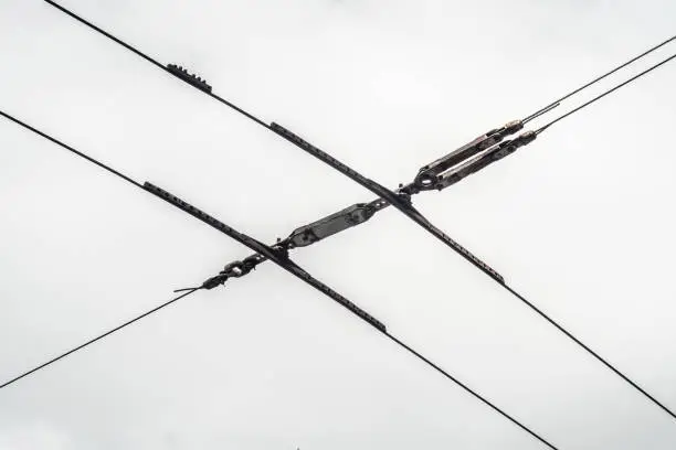 Old overhead trolleybus line isolated on white.Electrical wires against the cloudy sky.
