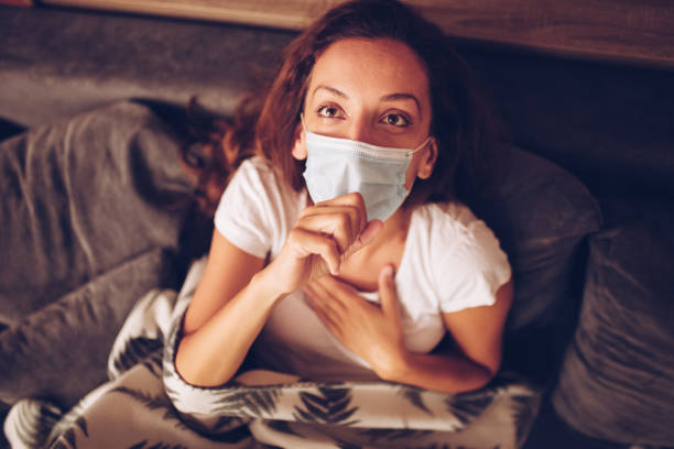 istock Girl lying in bed with cat wearing protective mask 1257190489