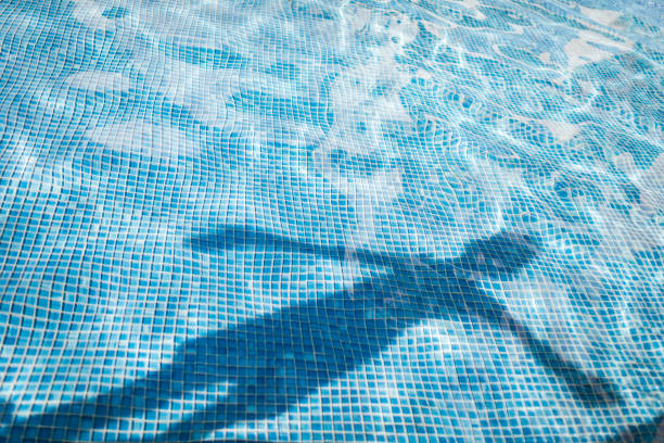 High angle view of man wearing red shorts swimming in a blue pool in sunny day at summer