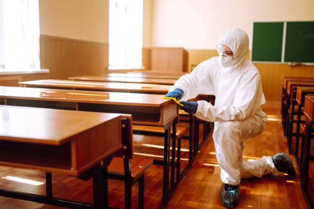 istock Man in a protective suit washes school desk. 1257199251