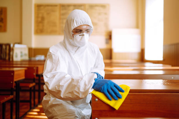 istock Man in a protective suit washes school desk. 1257199277