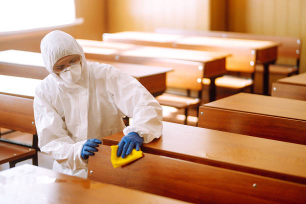 istock Man in a protective suit washes school desk. 1257199296
