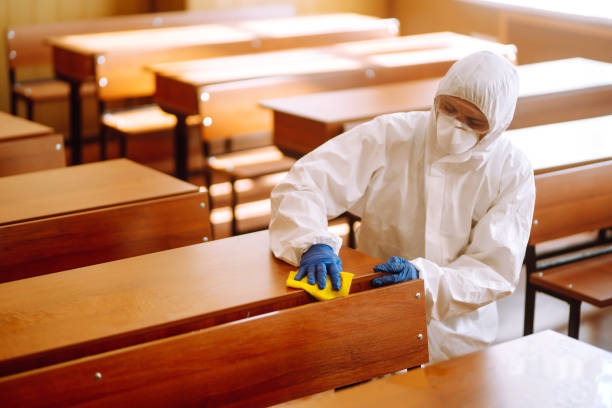 istock Man in a protective suit washes school desk. 1257199334
