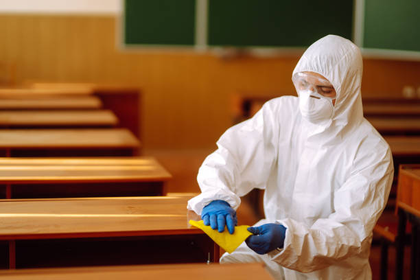 istock Man in a protective suit washes school desk. 1257199350