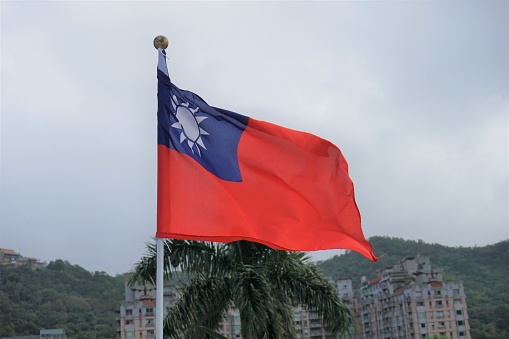The flag of Taiwan, consists of a red field with a blue canton bearing a white disc with twelve triangles surrounding it.