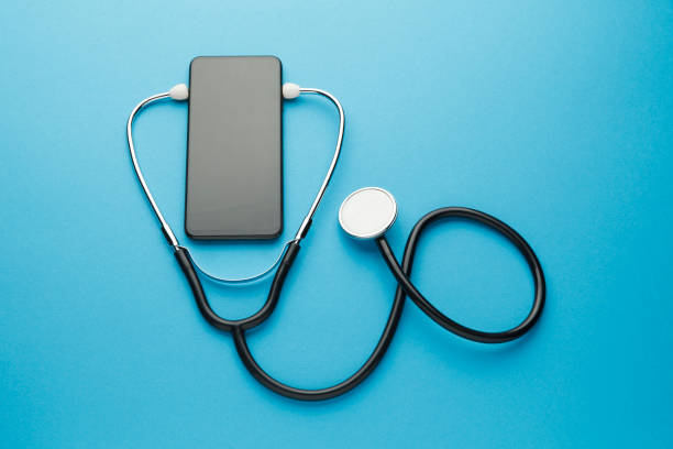 青い背景にスマートフォンと聴診器。オンライン医療(遠隔医療)技術。遠隔診断のためのサービス、医師とのチャット - language therapy ストックフォトと画像