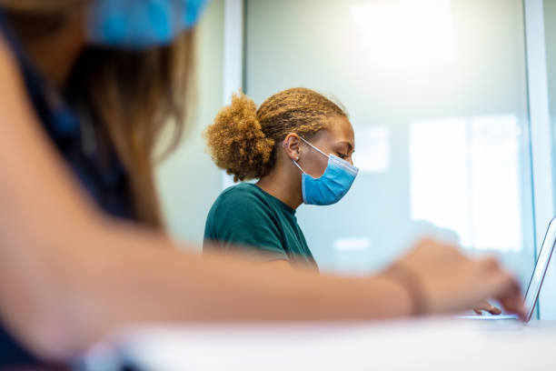 istock Two Female High School Students Social Distancing in Classroom Setting Wearing Masks 1257206841