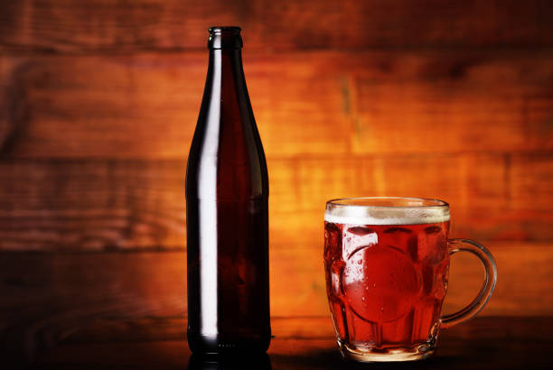 Big plastic beer bottle and two empty mugs on white background