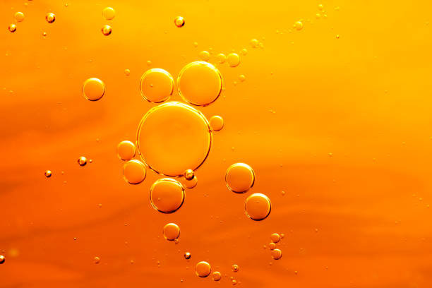 el aceite cae en el agua, burbujas sobre fondo abstracto naranja - splashing orange fruit water fotografías e imágenes de stock