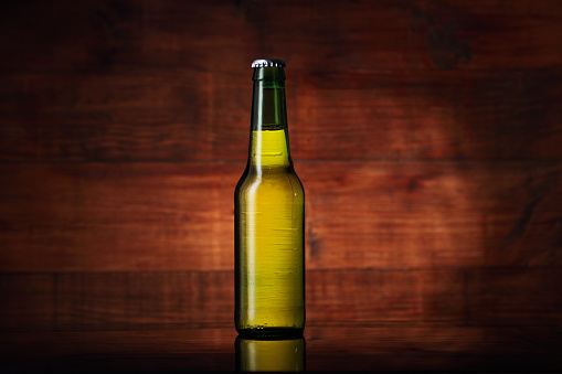 bottle of beer in a green bottle on a wooden background