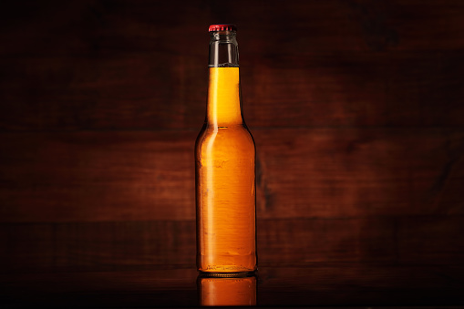small full bottle of light beer on a wooden background