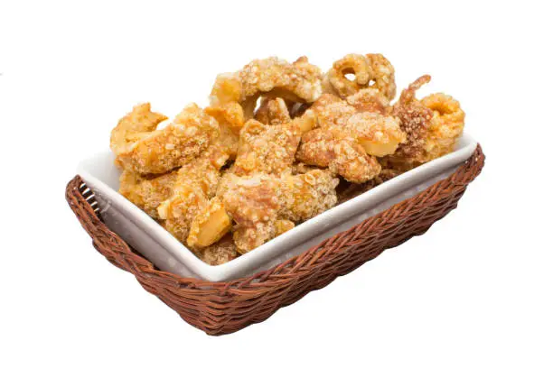 Photo of Pork crackling  traditional Brazilian recipe called torresmo in a platter isolated in white background