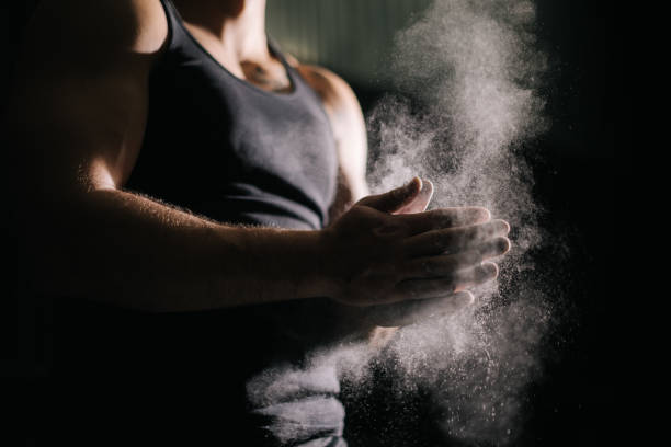 istock Close-up of unrecognizable muscular man clapping hands with talc and preparing for workout at gym. 1257213262