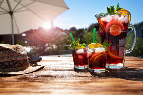 Summer drink on sunny terrace Jug fresh cold summer drink on a sunny terrace with parasol and straw hat on wooden table. Background for vacation and leisure. Short depth of field. blue jug stock pictures, royalty-free photos & images