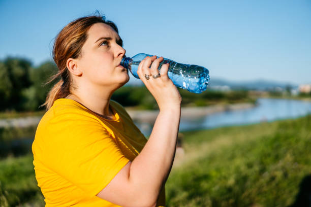 istock Oversized woman drinking water after running 1257215992