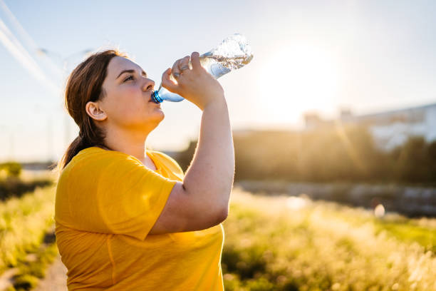 übergroße frau trinkwasser nach dem laufen - adult jogging running motivation stock-fotos und bilder