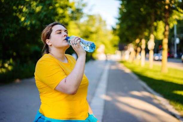 istock Oversized woman drinking water after running 1257216135