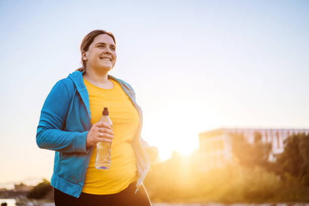 młoda kobieta z nadwagą biega - sun people jogging sunset zdjęcia i obrazy z banku zdjęć