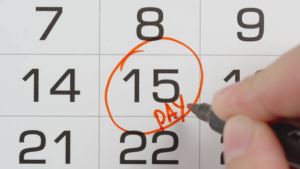 istock TOP VIEW: Marking a pay day in a calendar by red pen - Macro shot 1257219781