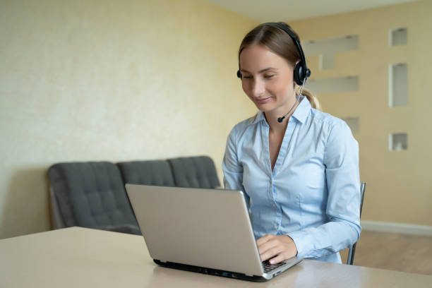 istock Woman wear headset communicating by conference call speak looking at computer at home office, video chat job interview 1257219943