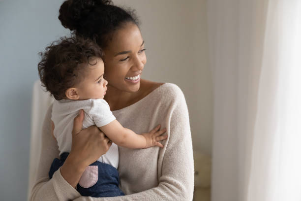 かわいい娘を抱く笑顔の夢のようなアフリカ系アメリカ人の母親 - newborn baby african ethnicity little girls ストックフォトと画像