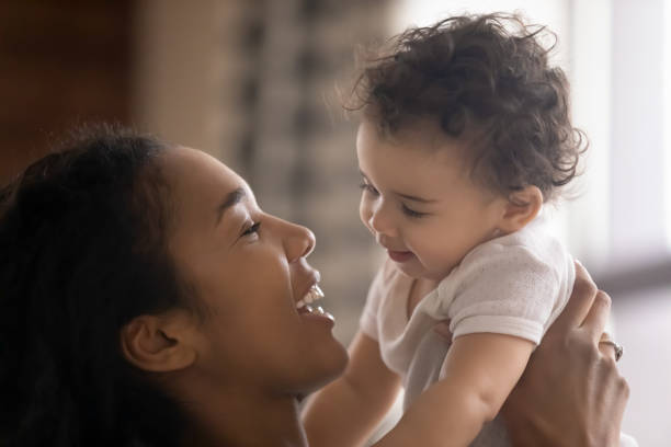 愛らしい小さな娘を保持している愛するアフリカ系アメリカ人の女性をクローズアップ - newborn baby african ethnicity little girls ストックフォトと画像