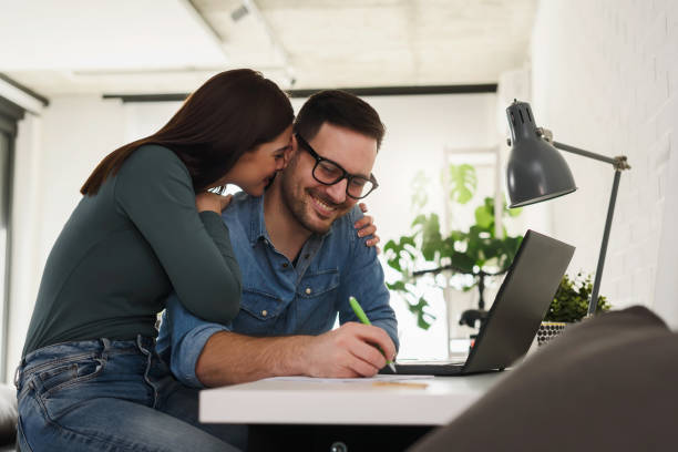 istock Young couple working from home. Man is working on a computer, and woman is supporting him. 1257226944