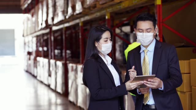 Business people in face mask as new normal talk in warehouse